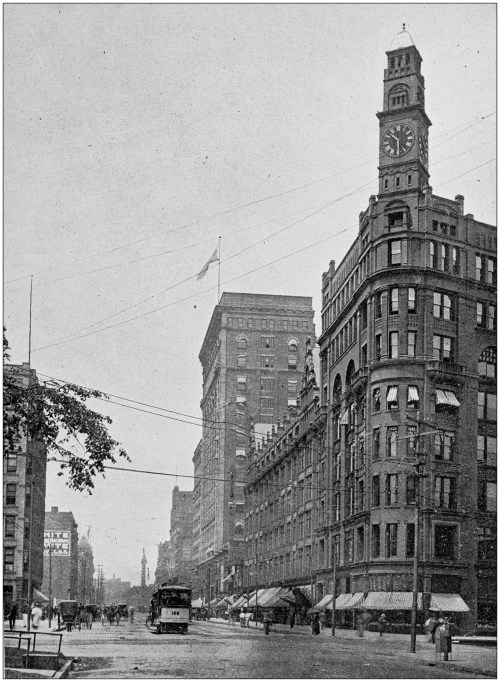 Historic city street scene featuring a clock tower, buildings, and a streetcar, with flags and power lines overhead.