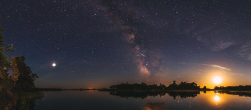 A serene lake at night, featuring a starry sky, the Milky Way, and a bright moon reflecting on the water.
