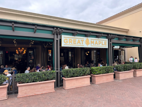 Exterior of Great Maple restaurant, featuring outdoor seating and a welcoming sign, with patrons dining and socializing.