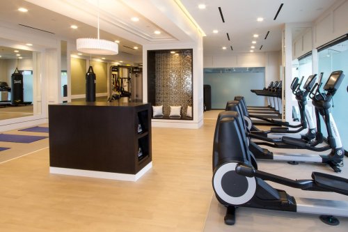 Modern gym interior featuring cardio machines, a central island, and a stylish relaxation area with decorative elements.