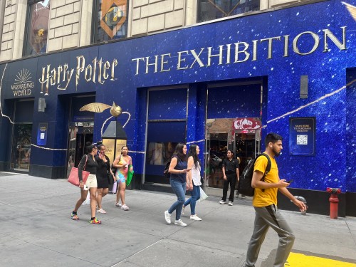 People walking in front of the Harry Potter: The Exhibition entrance, featuring a blue, starry facade.