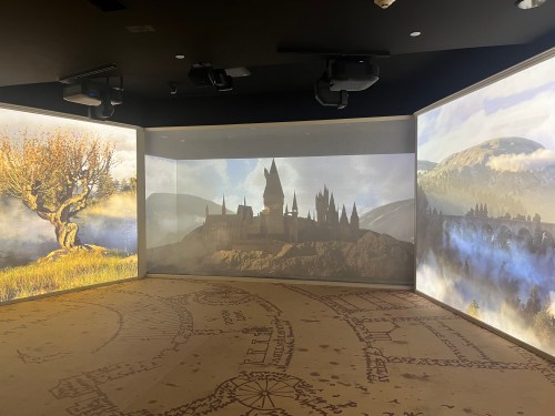 A dimly lit room with large screens displaying a castle silhouette and scenic landscapes.