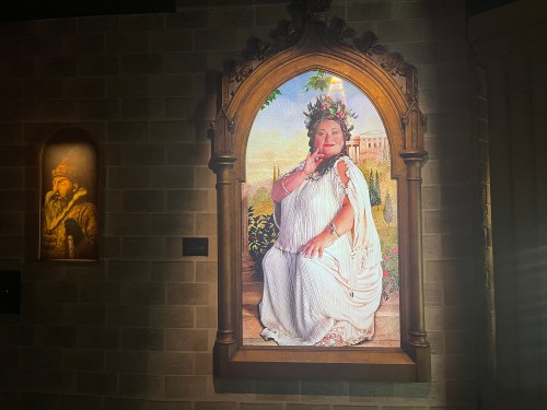A regal woman in a flowing white dress sits in a garden, adorned with flowers and a crown, framed in an ornate arch.