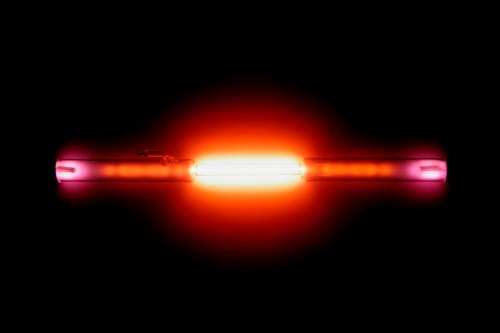 A glowing tube with vibrant orange and pink hues against a black background.