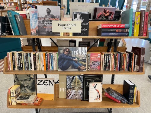 A wooden bookshelf displaying various books, including titles on art, music, and literature, labeled "Household Items."