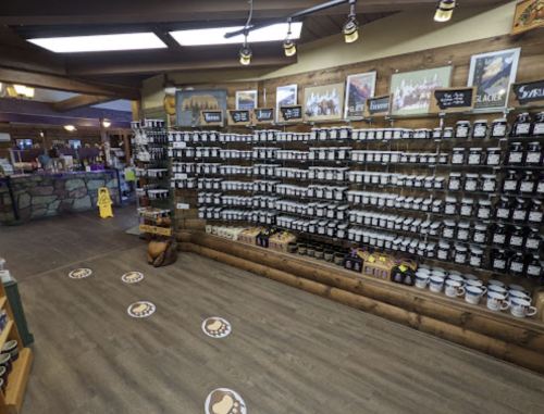 A wall display filled with jars and containers, with paw print markers on the floor in a rustic shop setting.