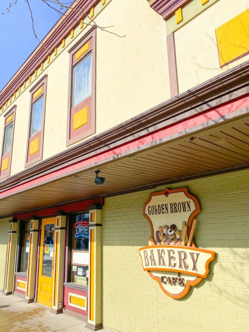 Exterior of the Golden Brown Bakery Cafe, featuring colorful signage and a welcoming entrance on a sunny day.