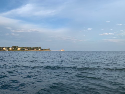 A calm sea under a blue sky, with distant land and a small structure visible on the horizon.