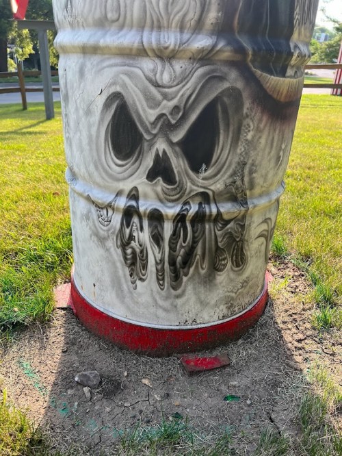 A close-up of a barrel featuring a ghostly skull design, set on grass with a red base.