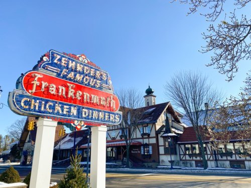 A colorful vintage sign for "Zehnder's Famous Frankenmuth Chicken Dinners" in front of a charming building on a clear day.