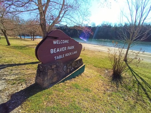 Welcome sign for Beaver Park at Table Rock Lake, surrounded by trees and a view of the water in the background.