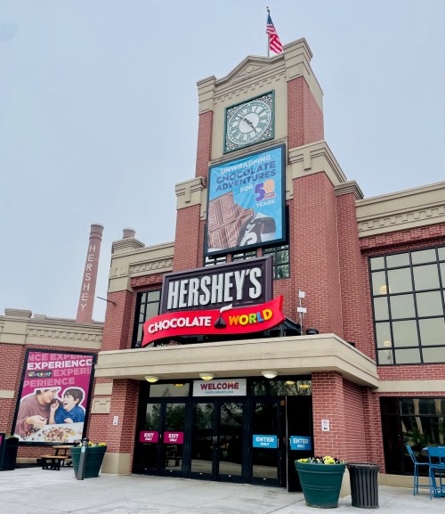 Entrance to Hershey's Chocolate World, featuring a large sign and promotional banners, with a clock tower above.