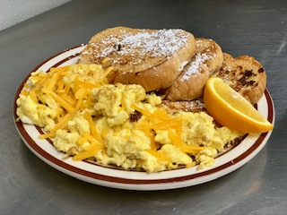 A plate of scrambled eggs with cheese, French toast, and a slice of orange.