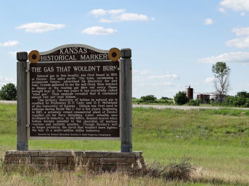 A historical marker in Kansas detailing the discovery of natural gas and its impact on the local industry.