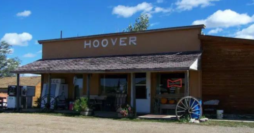 A rustic building with the name "HOOVER" on the front, featuring a porch and vintage decor under a blue sky.