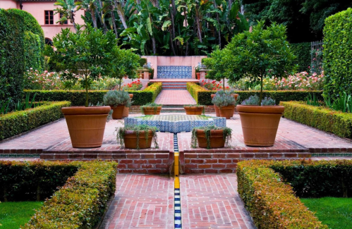 A beautifully landscaped garden with potted plants, brick pathways, and vibrant flowers in a serene setting.