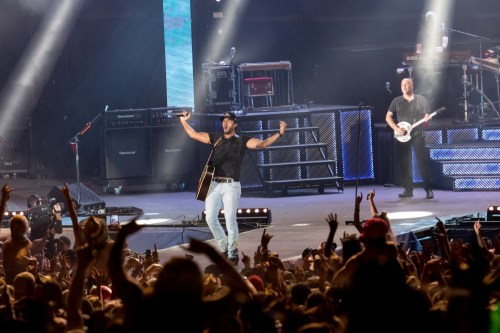 A lively concert scene with a singer performing on stage, surrounded by an enthusiastic crowd.