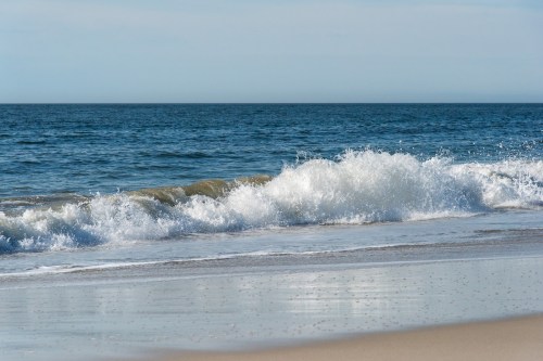 Waves gently crashing on a sandy beach under a clear blue sky.