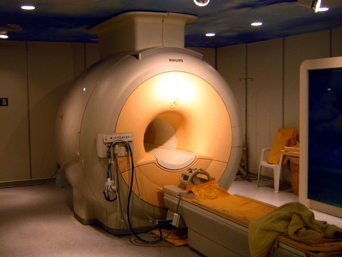 A modern MRI machine in a clinical setting, with a patient bed and soft lighting.