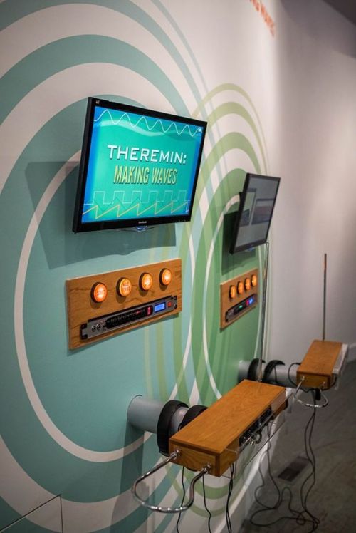 Exhibit display featuring a theremin with controls and screens titled "Theremin: Making Waves."