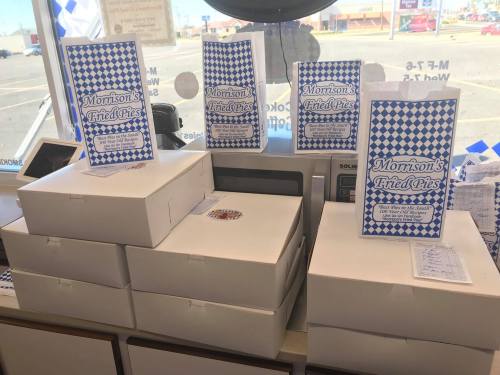 Boxes of Morrison's Fried Pies stacked on a counter, with promotional signs displayed in front.