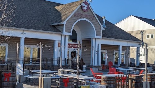 Exterior of a restaurant with a large entrance, outdoor seating, and festive decorations, set against a clear blue sky.