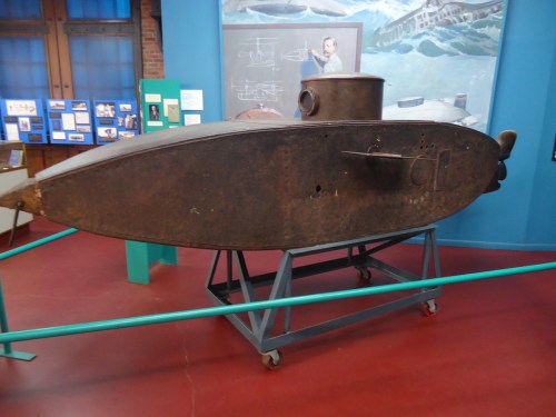 A vintage submarine model displayed in a museum, showcasing its metal structure and historical significance.