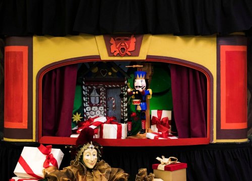 A colorful puppet stage with a king puppet, surrounded by wrapped gifts and a decorative backdrop.