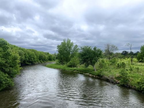 A winding river flows through lush greenery under a cloudy sky.
