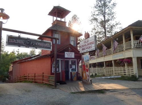 A rustic building with a sign for a brewery, surrounded by trees and American flags, in a charming old town setting.