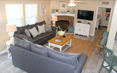 Cozy living room with gray sofas, a wooden coffee table, and a fireplace, featuring light decor and a TV.