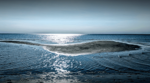 A serene seascape with gentle waves reflecting sunlight, creating a tranquil atmosphere on the water's surface.