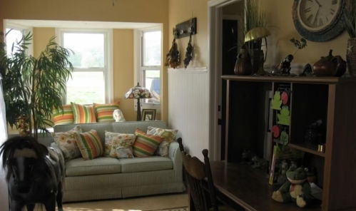 Cozy living space with a striped sofa, decorative plants, and a wooden desk, featuring warm natural light.