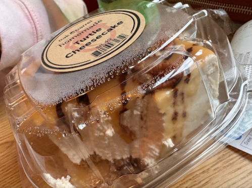 A close-up of a container holding a slice of homemade turtle cheesecake, with condensation on the lid.