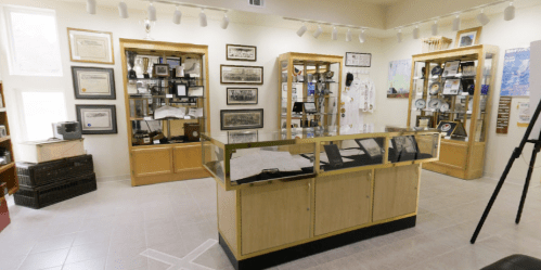 A museum display featuring glass cases with artifacts, framed documents, and various awards on the walls.