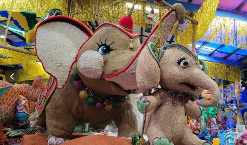 Colorful, large elephant and whimsical character made of decorative materials, set against a festive backdrop.