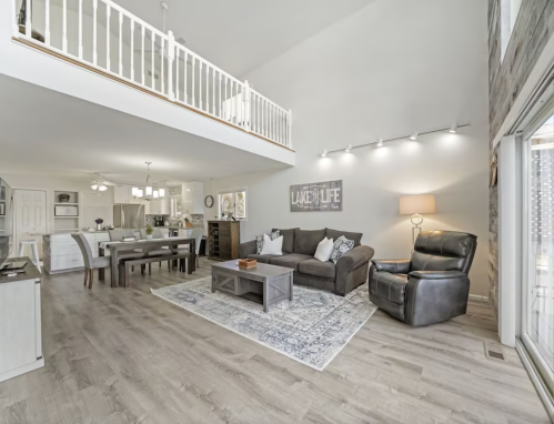 Spacious living area with a sofa, dining table, and large windows, featuring modern decor and a cozy atmosphere.