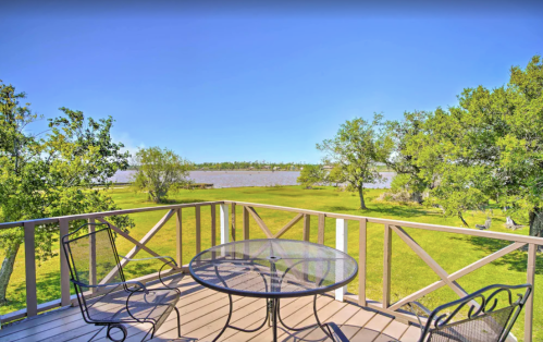 A scenic view from a balcony overlooking a river and lush green landscape under a clear blue sky.