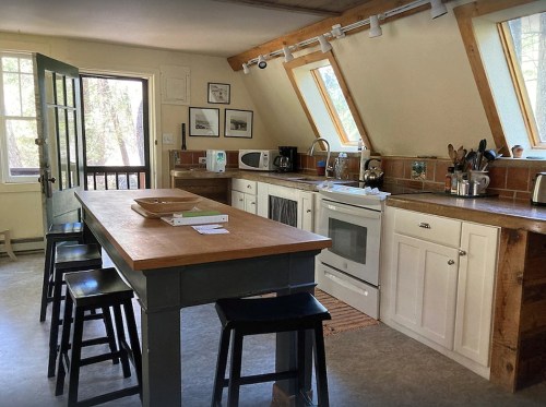 A cozy kitchen with a wooden island, modern appliances, and large windows letting in natural light.