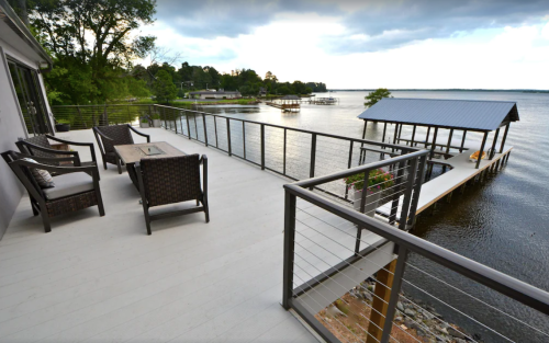 A serene lakeside deck with seating and a boat dock under a cloudy sky.