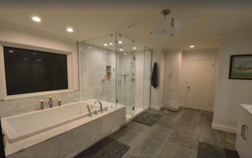 Modern bathroom featuring a glass shower, freestanding tub, and elegant tile flooring. Soft lighting enhances the space.