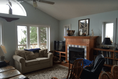 Cozy living room with a sofa, fireplace, TV, and large windows overlooking a scenic view.