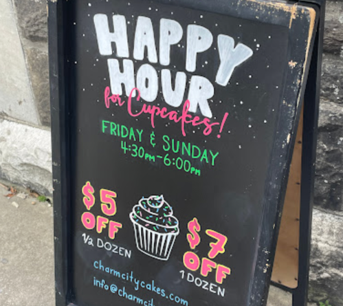Chalkboard sign advertising cupcake happy hour on Fridays and Sundays, with discounts for half and full dozen.