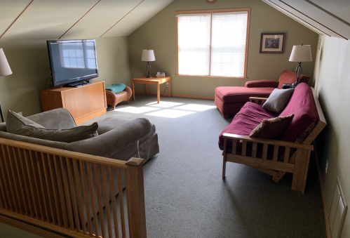 Cozy attic living space with a TV, two sofas, a coffee table, and natural light from a window.
