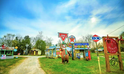 A nostalgic roadside scene featuring vintage gas station signs and a large bear statue, set against a blue sky.