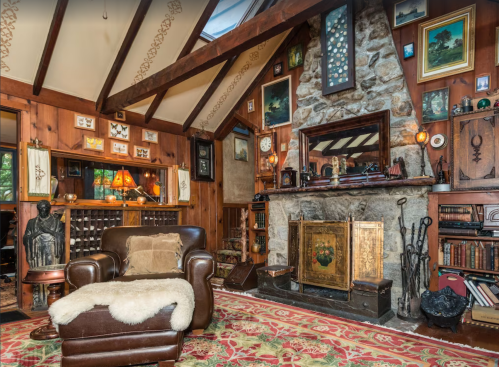 Cozy living room with wooden walls, a stone fireplace, vintage decor, and a comfortable leather armchair.