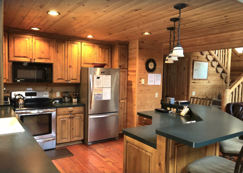 Cozy wooden kitchen with stainless steel appliances, a large island, and warm lighting.
