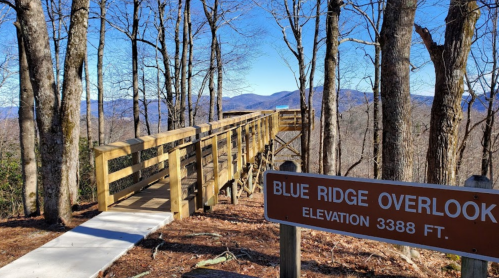 A wooden overlook platform in a forest, with a sign reading "Blue Ridge Overlook, Elevation 3388 ft," and mountains in the background.