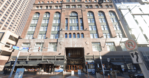 Historic building facade with large windows and decorative elements, featuring shops at street level.