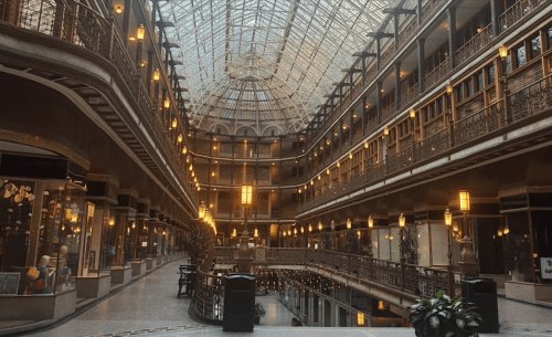 A spacious, elegant atrium with glass ceiling, balconies, and warm lighting in a historic building.